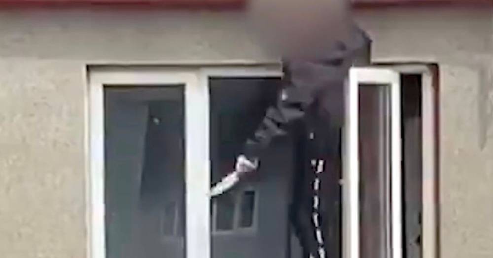 Dramatic images show knife-wielding man hanging from window above riot cops in Ayrshire street - www.dailyrecord.co.uk - Scotland - city Irvine