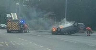 Road closed as car catches fire after being 'flipped' onto roof during collision - www.manchestereveningnews.co.uk