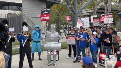 Dispatches From The Picket Lines, Day 24: Sen. Gillibrand Addresses NY Crowd; In L.A., Lil Wayne Sends Burgers, A Robot Pickets & A Marching Band Plays Outside Warners & NBCU - deadline.com - New York